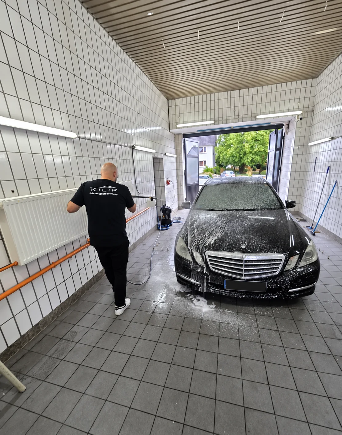 Mitarbeiter bei der Schaumwäsche eines Mercedes-Benz in der KILIF-Mobility-Waschhalle